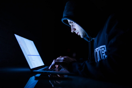 在罩在膝上型电脑黑客破解程序在夜间工作的人照片