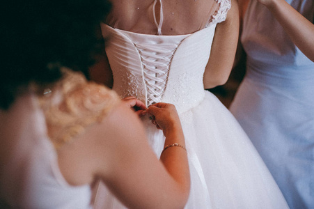 时尚伴娘礼服帮助的磨损弓上背婚礼礼服新娘。婚礼那天早上