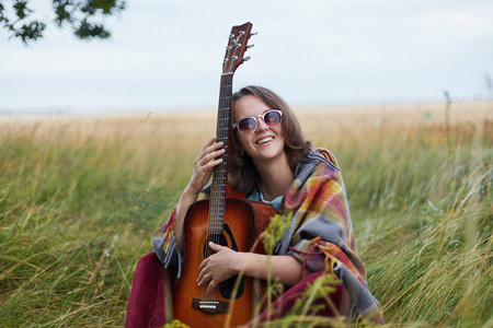 年轻女性穿着随随便便拿着吉他在相机都有好心情,户外休息,欣赏壮丽的