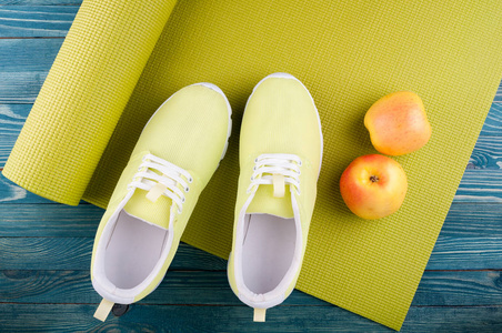 体育背景。瑜伽垫，运动鞋，木制背景的苹果果实。健康的生活方式 饮食 瑜伽 体育概念