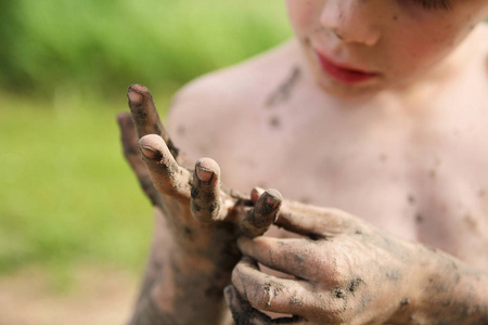 小男孩从肮脏的手上摘下泥巴