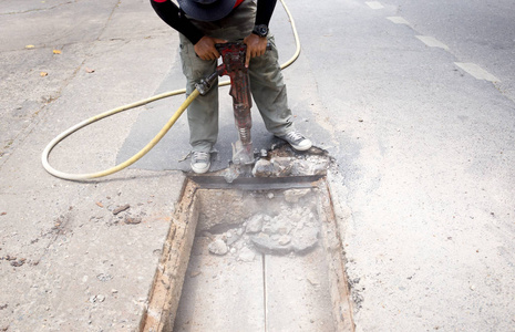 在道路现场工作的工人用气尘拆除沥青