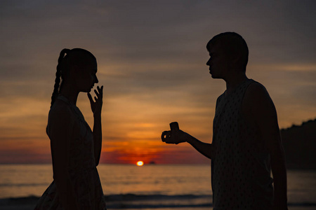 weddingcouple向与日出背景剪影女人的剪影男子求婚照片