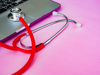 医用听诊器和一台笔记本电脑上粉红色表格背景