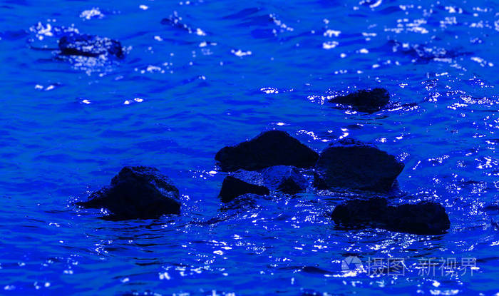 深蓝色水中的黑色石头