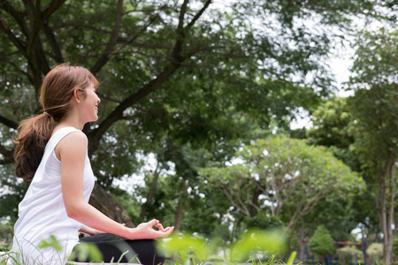 在户外在公共公园的瑜伽。亚洲女人坐在荷花的立场