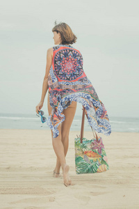 女游客在太阳镜和沙滩袋轻松旅行度假的热带夏季度假海滩上行走。年轻的女士，在印度尼西亚巴厘岛豪华时尚沙滩装