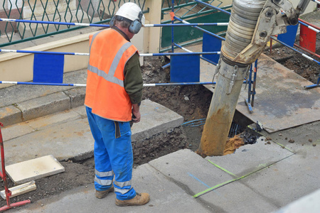 穿制服的沥青工人控制钻井过程。破碎混凝土道路施工现场