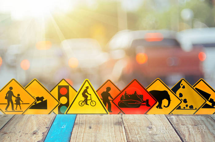 模糊交通道路上的一套交通警告标志,有五颜六色的bokeh灯和旧的空木桌