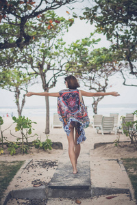 自由的概念。在披肩和泳装，沙滩袋进入海滩的年轻女子。热带岛屿巴厘岛印度尼西亚