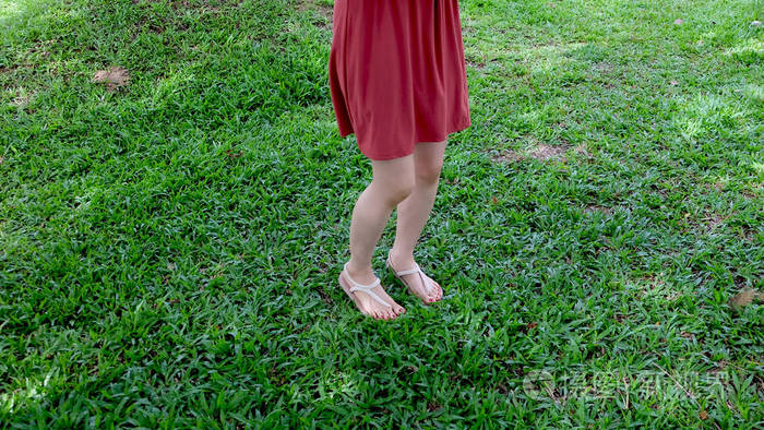 在绿色草地上穿着凉鞋的女孩的脚上特写
