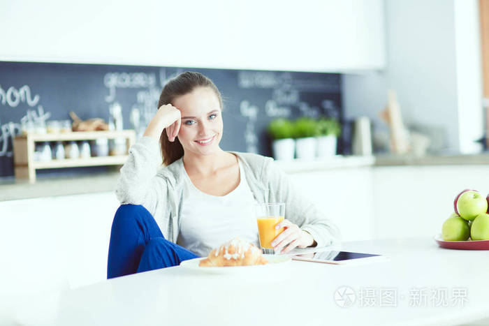 桔子汁和平板电脑在厨房里的年轻女子