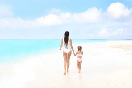 美丽的年轻女子，与她的女儿在海水浴场的沙滩上