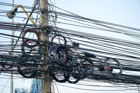 在电线杆上的杂乱的电缆和电线, 蓝天背景。复杂电气设备概念