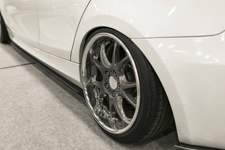 轮胎和合金车轮的现代白色汽车在地面。汽车外部细节
