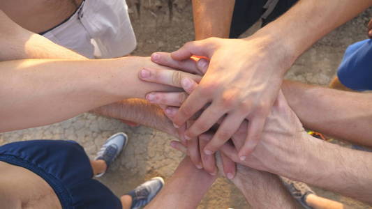 运动员团队在户外手臂合二为一.一群人在外面携手共进.