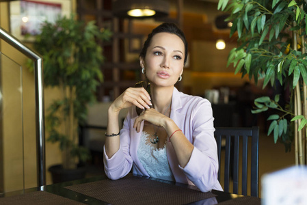 美丽的女人坐在现代咖啡厅酒吧，思考新的想法的年轻迷人女性自由职业者梦到的东西