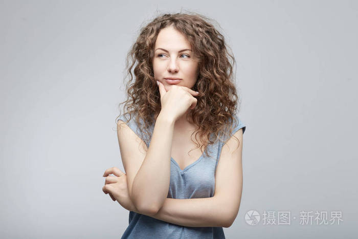 美丽穿着随意的年轻白人女子有怀疑的表情,看着别处狡猾地在犹豫不决