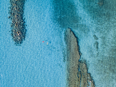 独木舟上透明的海上漂浮的水的鸟瞰图。泳客在海上。意大利卡拉布里亚，邸西巴里。暑假和潜水的放松。意大利的海岸 海滩和岩石