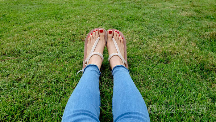 站在绿草背景上的金凉鞋中的脚自拍