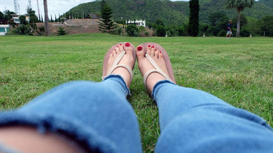 站在绿草背景上的金凉鞋中的脚自拍