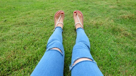 站在绿草背景上的金凉鞋中的脚自拍