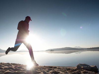 男孩很快跑在早晨的海滩上.运动员跑步,跑步的家伙照片