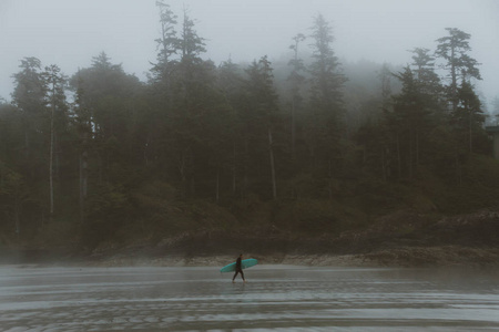 冲浪者在雾中走在沙滩上