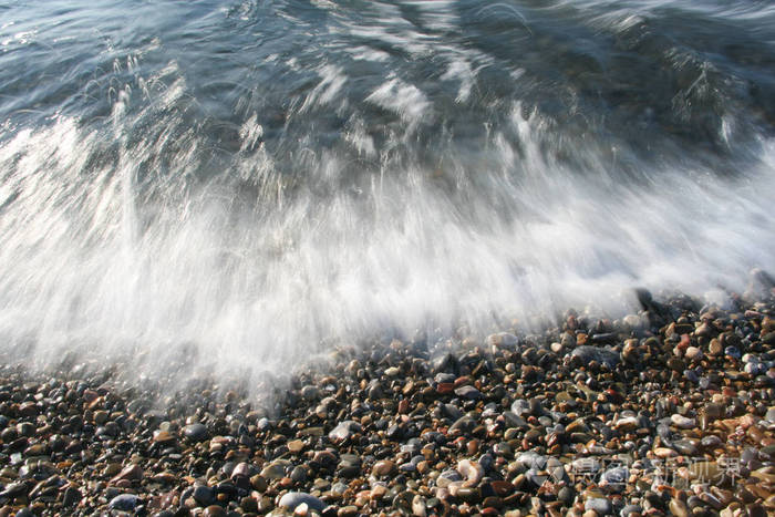 鹅卵石海滩上的海上冲击波泡沫