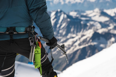 一个年轻小伙子登山者近距离他的手里拿着冰斧站在高山区的首脑会议。极限运动概念