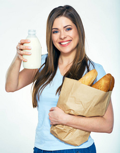微笑快乐的女人抱着纸袋用面包和显示牛奶