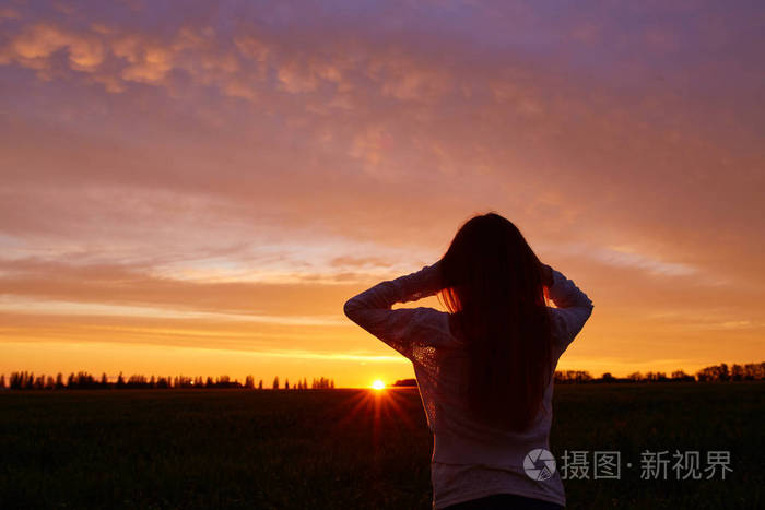 一个女人在早上黎明的背景上的白色裙红色卷发