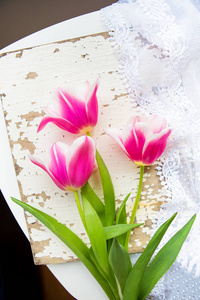 三个美丽的粉红色郁金香，老白桌上
