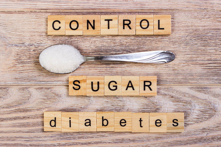 糖尿病控制块木制字母和糖堆上一勺子