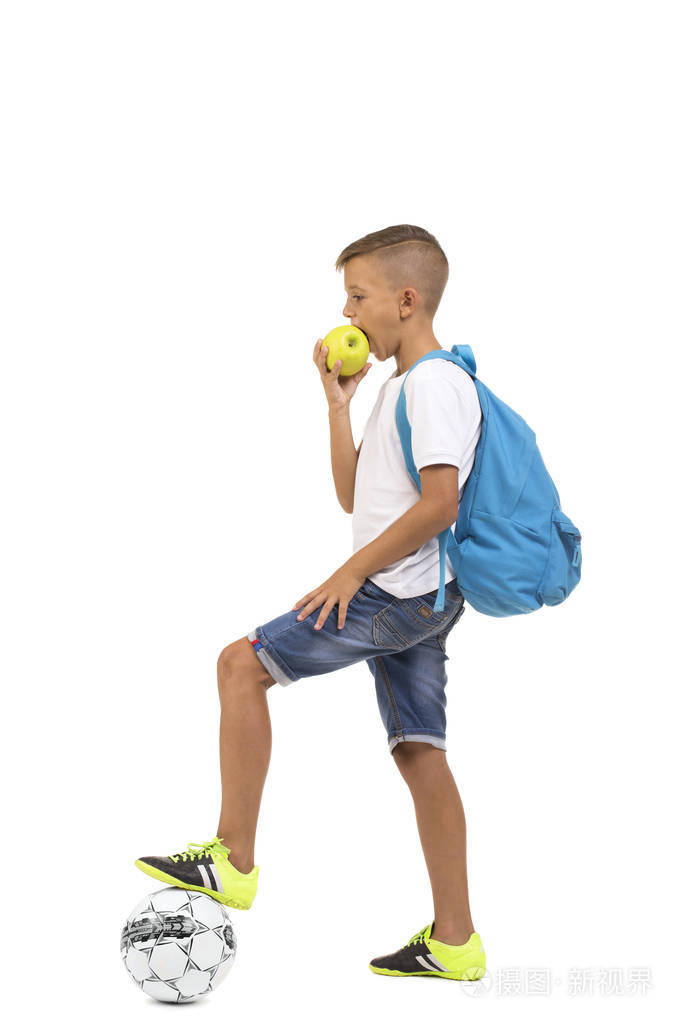 孤立在白色背景上的小学生吃苹果。学生冲一个足球。学校橄榄球和足球理念