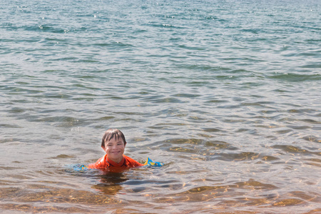 男孩与唐斯综合症在水中在海滩