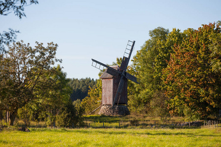 古老的木制风车在草甸与树木。秋天的时间