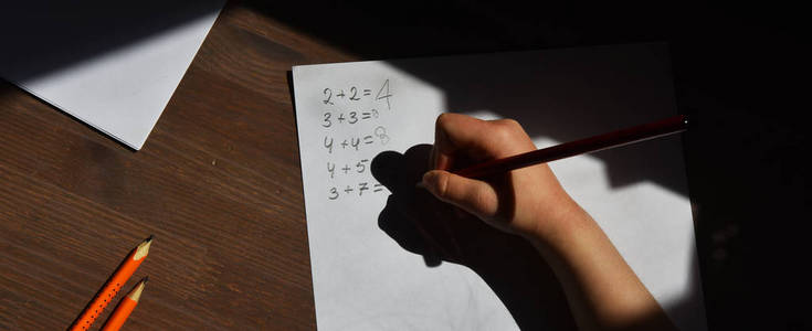 孩子们用铅笔的手解决数学例子