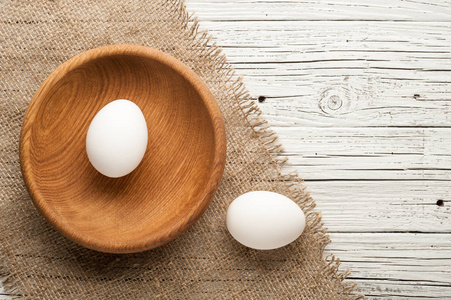 在白色的木制背景上的木制板鸡鸡蛋