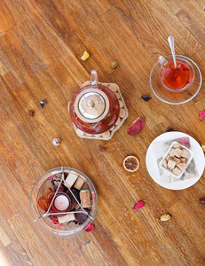 茶和饼干的最高视图。在木制背景下的香味蜡烛和一杯红茶。花式水壶和水果茶