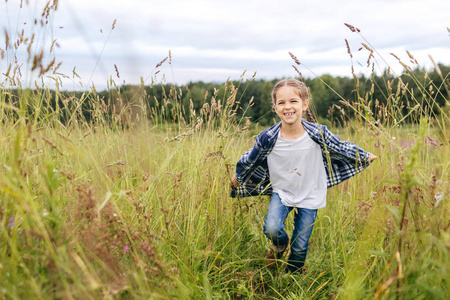 小可爱女孩跑在草原上，有快乐的表达，同时享受美丽的大自然。可爱的女孩在绿草上运行独自玩乐。童年 生活方式 松弛概念