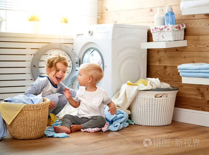 快乐的孩子男孩和女孩在洗衣负荷洗涤机