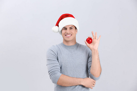 英俊的男人，在圣诞帽子控股闪亮摆设在明亮的背景上