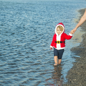 圣诞老人服装走在海滩上的男孩