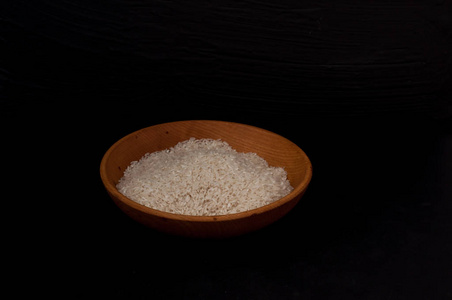 米在木碗与木勺在黑色背景空白空间