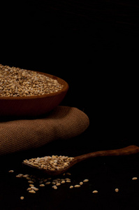 全谷物的珍珠大麦或小麦洒在右黑色背景。农业食品原料种子