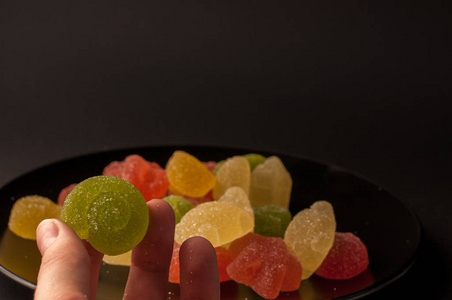 五彩缤纷的糖果的特写镜头。混合的水果味果冻在黑色印版上