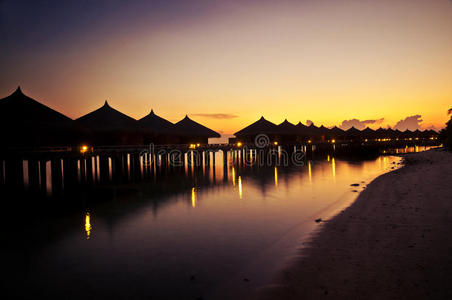 日落时海滩上的热带小屋