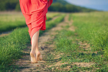 夏日天草背景下一位身着红色连衣裙的美丽年轻女子的画像