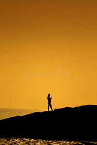 孕妇站在海上岩石上的剪影